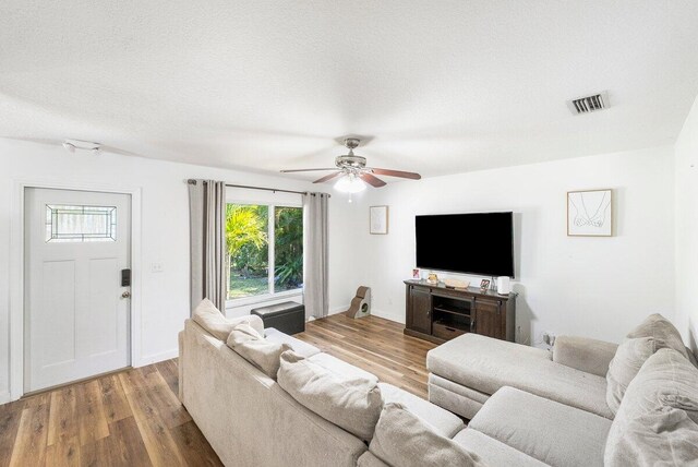 living room featuring visible vents, a textured ceiling, and wood finished floors