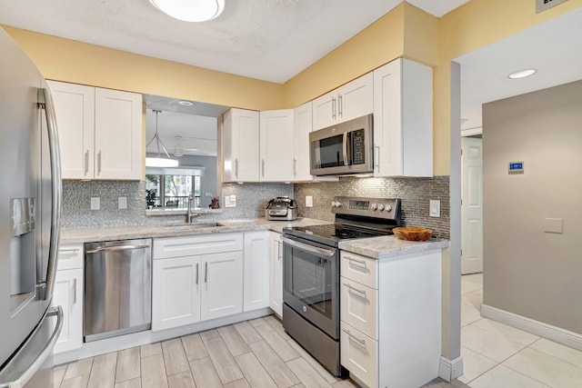 kitchen featuring stainless steel appliances, decorative backsplash, a sink, and white cabinets