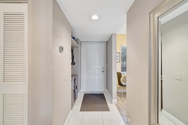 hall featuring light tile patterned floors and baseboards