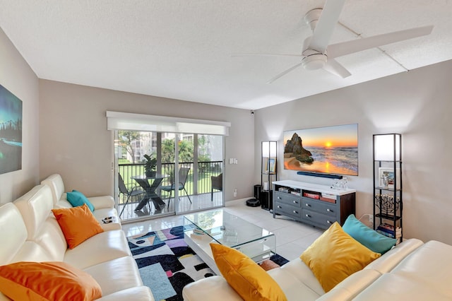 living area with ceiling fan, a textured ceiling, and light tile patterned floors