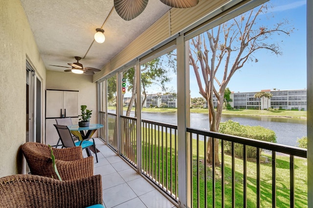 sunroom / solarium featuring a water view and a ceiling fan