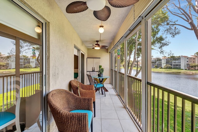 sunroom / solarium featuring a water view and a ceiling fan