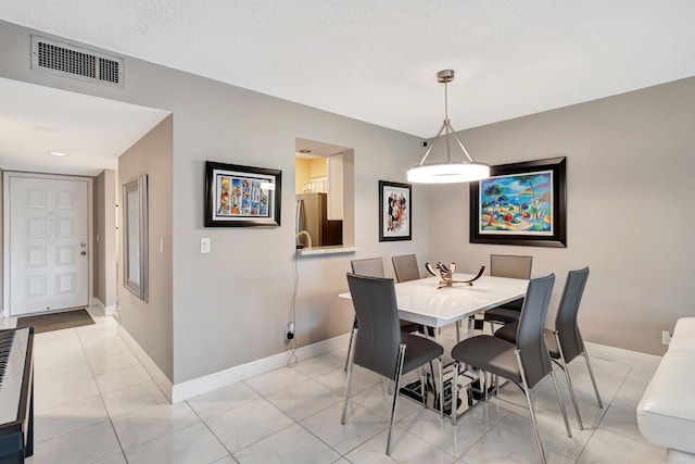 dining space featuring visible vents, a textured ceiling, and baseboards