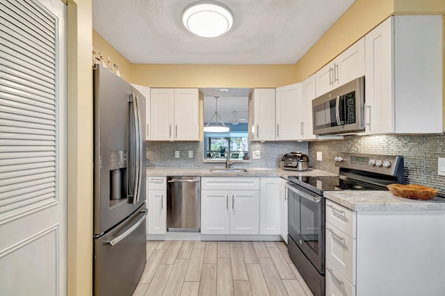 kitchen with stainless steel appliances, backsplash, a sink, and white cabinetry