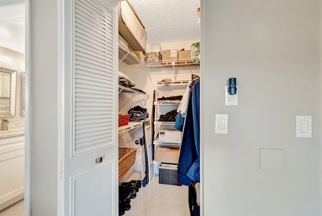 spacious closet with a sink and light tile patterned floors