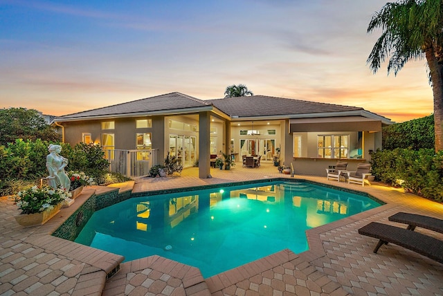 pool at dusk with a patio area and a fenced in pool