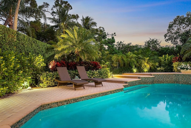 pool at dusk featuring a patio area and an outdoor pool