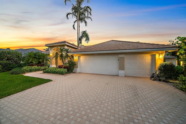 view of front facade with a garage, decorative driveway, and stucco siding