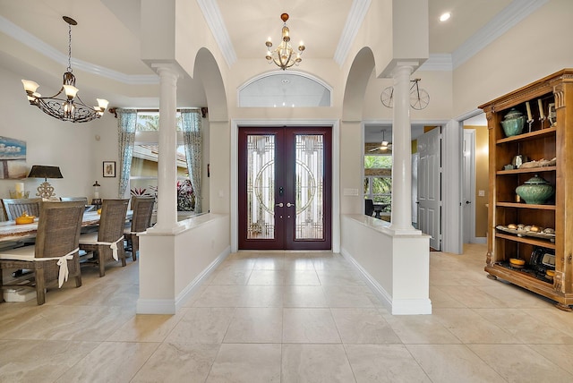 foyer with french doors, crown molding, a notable chandelier, ornate columns, and baseboards