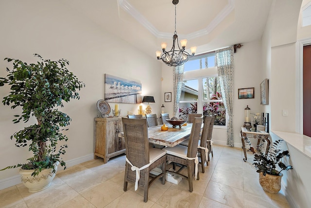 dining area featuring a tray ceiling, a notable chandelier, a high ceiling, ornamental molding, and baseboards