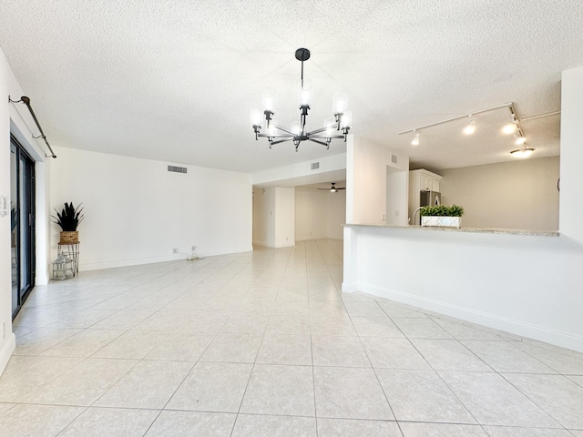 unfurnished room featuring light tile patterned floors, visible vents, a textured ceiling, and ceiling fan with notable chandelier