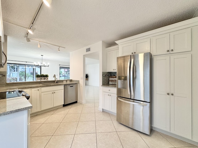 kitchen featuring light tile patterned floors, tasteful backsplash, visible vents, stainless steel appliances, and a sink