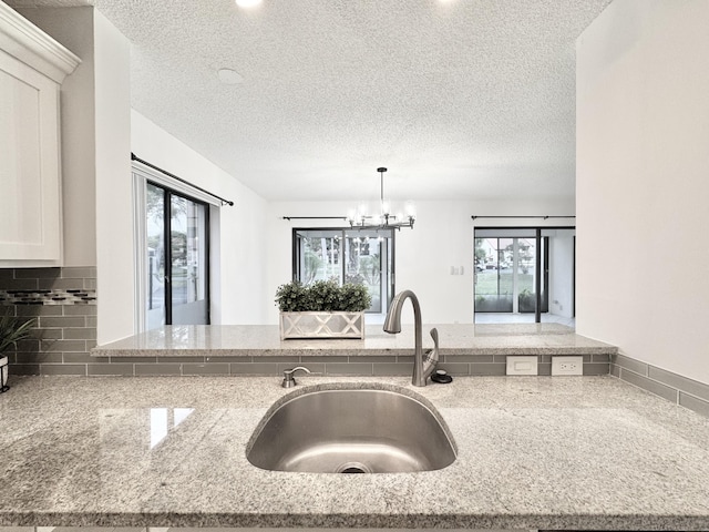 kitchen featuring light stone countertops, plenty of natural light, decorative backsplash, and a sink