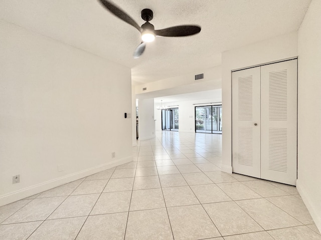 spare room featuring ceiling fan, a textured ceiling, light tile patterned flooring, visible vents, and baseboards