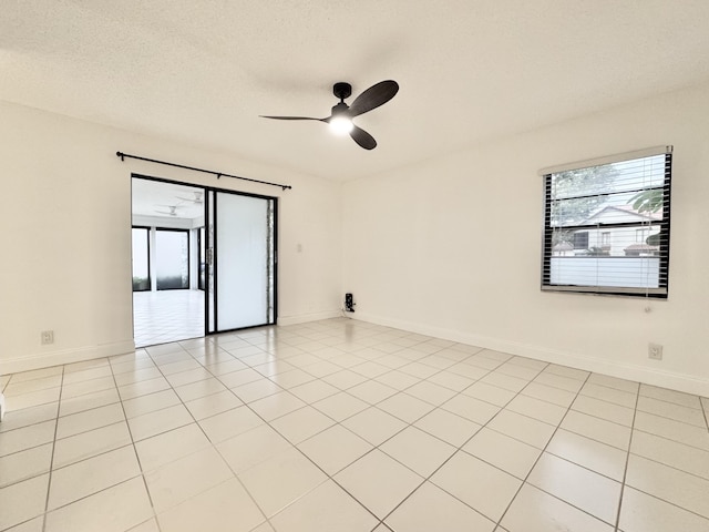 unfurnished room with ceiling fan, a textured ceiling, plenty of natural light, and baseboards