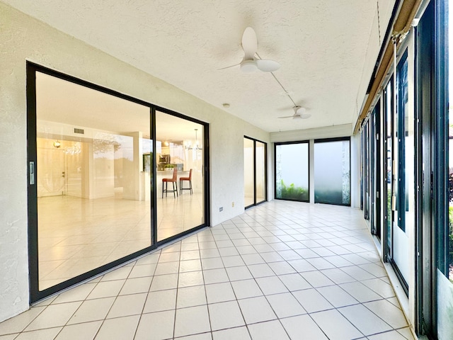 unfurnished sunroom featuring ceiling fan and a wealth of natural light