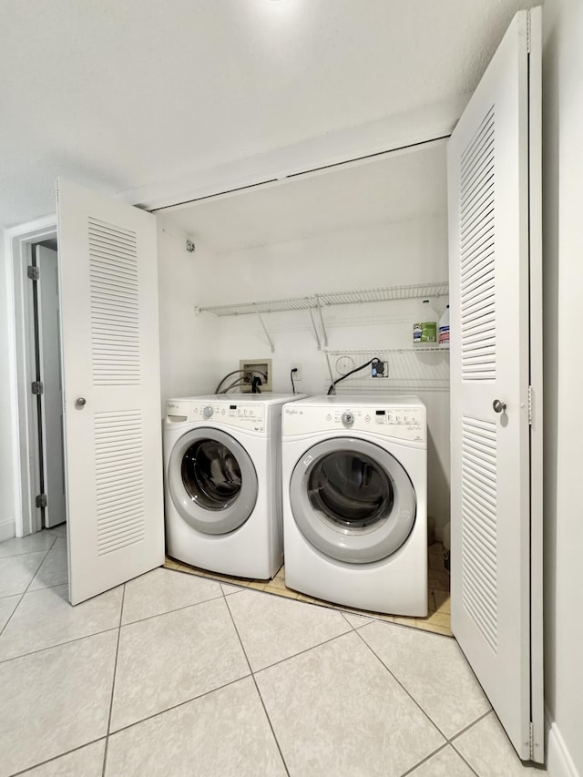 laundry room featuring light tile patterned floors, laundry area, and washing machine and dryer