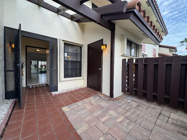 view of exterior entry featuring fence and stucco siding