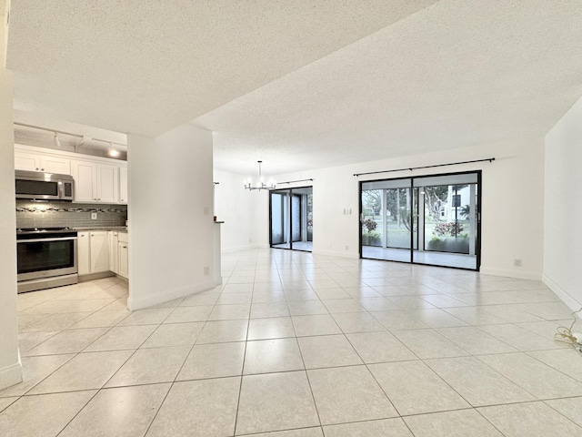 interior space featuring light tile patterned floors, a textured ceiling, baseboards, and an inviting chandelier