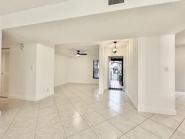 unfurnished room with light tile patterned floors, a ceiling fan, visible vents, and a textured ceiling