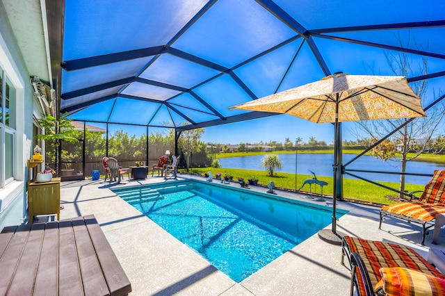 pool featuring a patio area, glass enclosure, a yard, and a water view