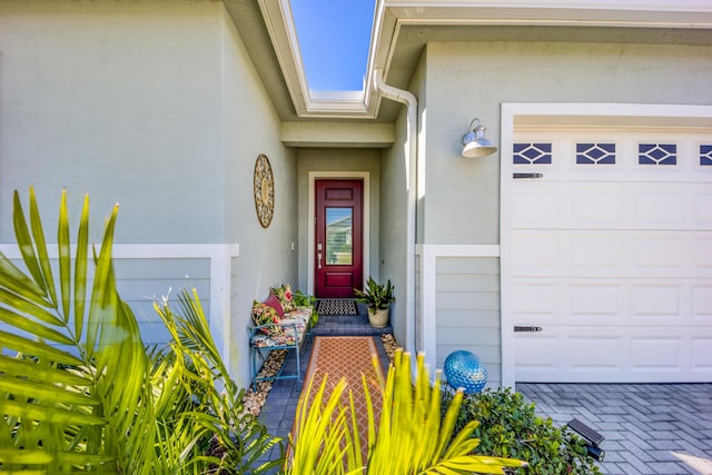 property entrance featuring a garage and stucco siding