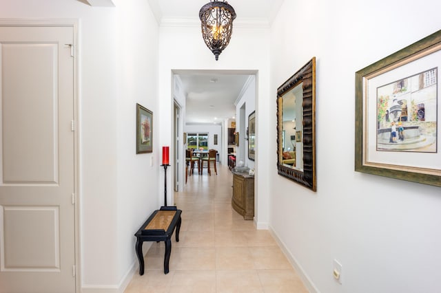 hall with light tile patterned floors, baseboards, and ornamental molding