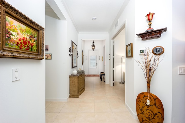 corridor with light tile patterned floors, visible vents, baseboards, and ornamental molding