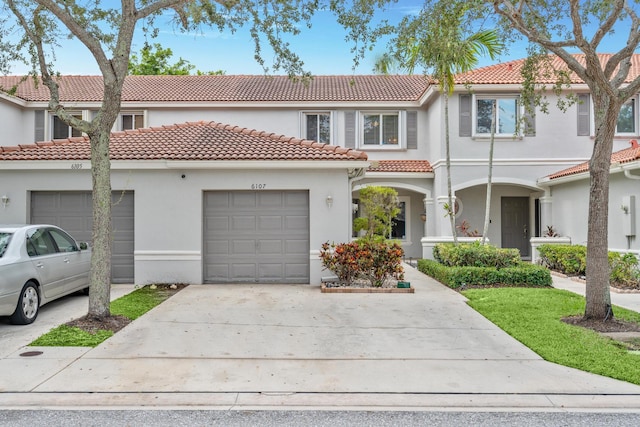 view of front facade featuring a garage, a tiled roof, concrete driveway, and stucco siding