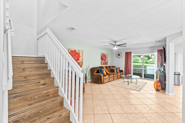 living area with visible vents, stairway, ceiling fan, and light tile patterned flooring