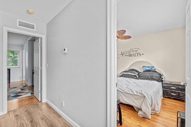 bedroom with wood finished floors, visible vents, and baseboards