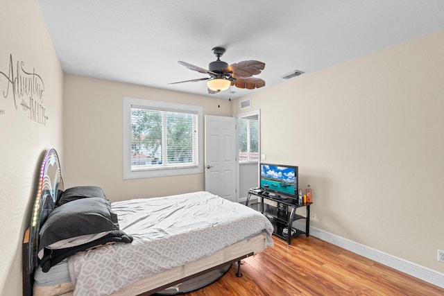 bedroom with visible vents, baseboards, ceiling fan, and wood finished floors