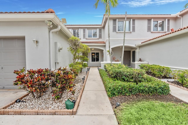 property entrance with an attached garage, a tile roof, and stucco siding