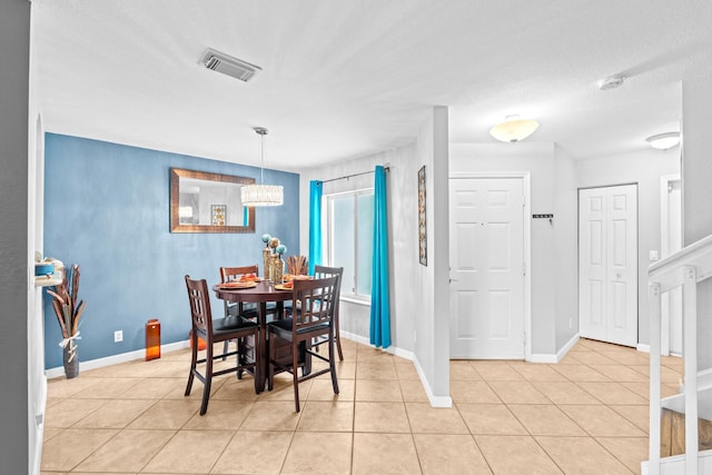 dining area with light tile patterned floors, baseboards, visible vents, and a notable chandelier