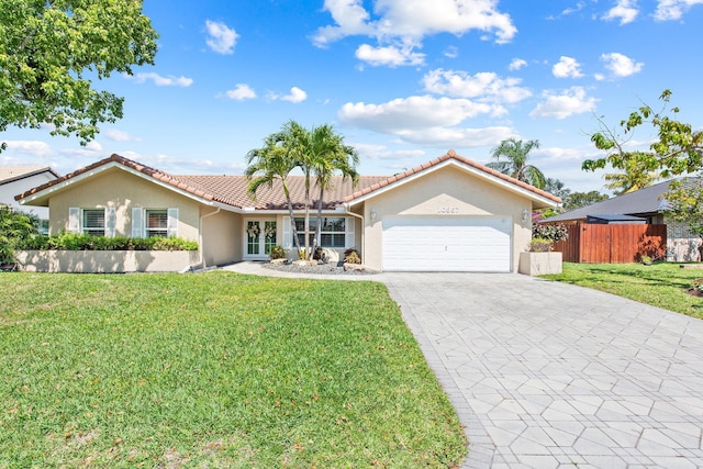 view of front of house with fence, a tile roof, a front yard, stucco siding, and an attached garage