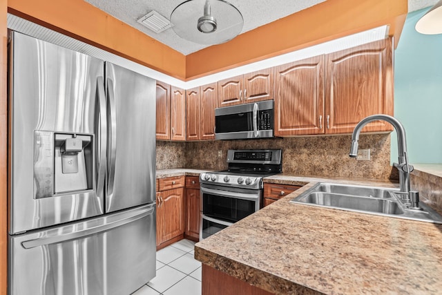 kitchen with light tile patterned floors, a textured ceiling, stainless steel appliances, a sink, and tasteful backsplash