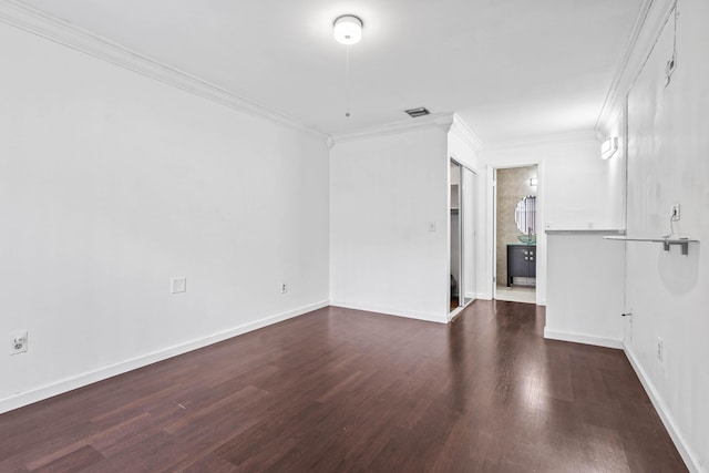 empty room featuring baseboards, visible vents, ornamental molding, and wood finished floors