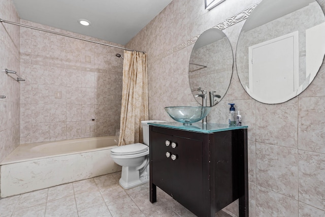 bathroom featuring toilet, tile patterned floors, shower / bathtub combination with curtain, vanity, and tile walls