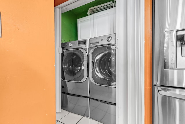 washroom with tile patterned flooring, washing machine and clothes dryer, and cabinet space