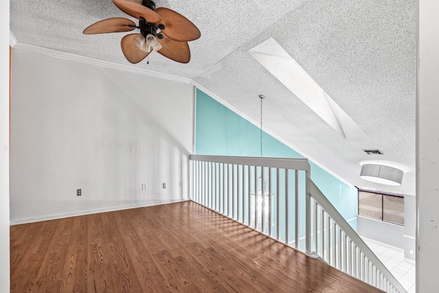 additional living space featuring lofted ceiling, ceiling fan, a textured ceiling, wood finished floors, and visible vents