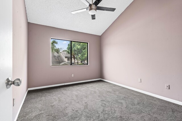 carpeted empty room with baseboards, vaulted ceiling, and a textured ceiling