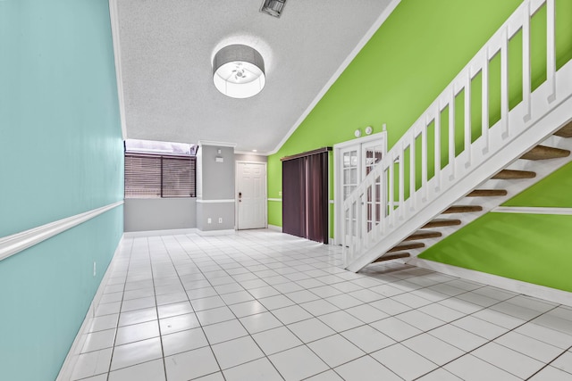 foyer entrance with vaulted ceiling, ornamental molding, a textured ceiling, and stairway