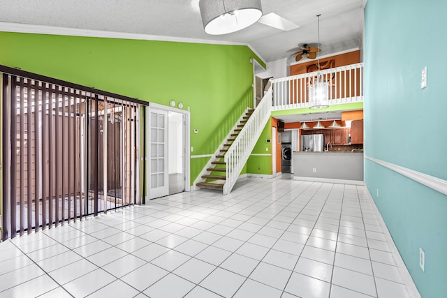 unfurnished living room with baseboards, stairway, tile patterned floors, washer / clothes dryer, and crown molding