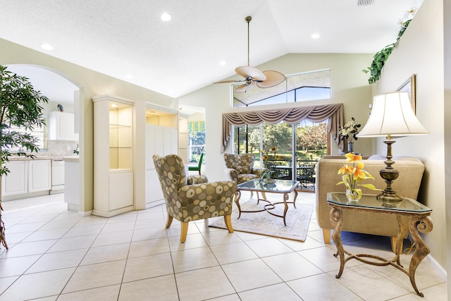 living area with light tile patterned floors, visible vents, vaulted ceiling, and a ceiling fan