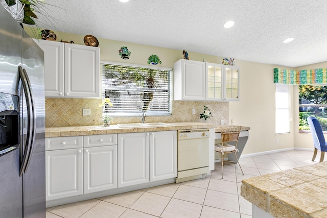 kitchen featuring dishwasher, a sink, stainless steel fridge, and tile counters