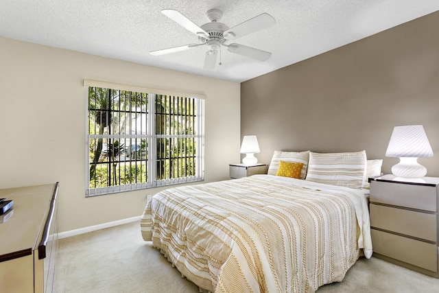 bedroom featuring baseboards, a textured ceiling, a ceiling fan, and light colored carpet