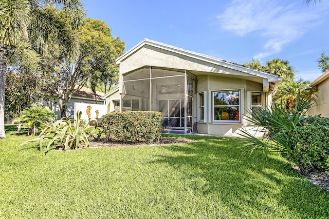 view of front of property featuring a sunroom, a front lawn, and stucco siding