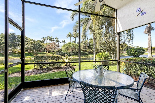 sunroom featuring a wealth of natural light, a water view, and a ceiling fan