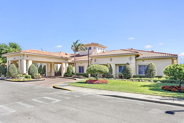 mediterranean / spanish-style home with a tile roof, a front lawn, and stucco siding