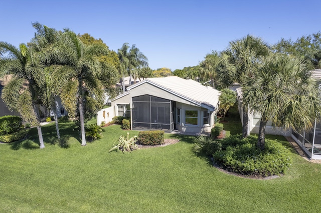 rear view of house featuring a lawn and a sunroom